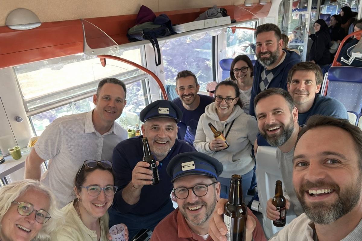 Un groupe hilare, casquettes de contrôleur sur la tête, dans un train rétro